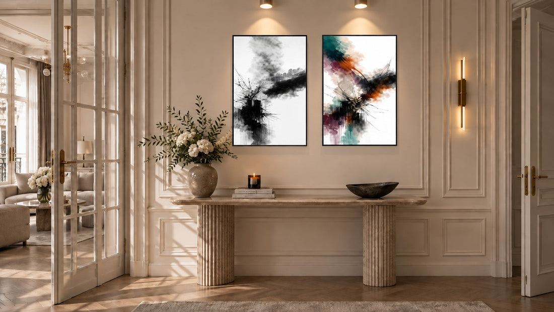Two framed abstract prints, one black-and-white and one colourful, above a travertine console in a Parisian-style entryway