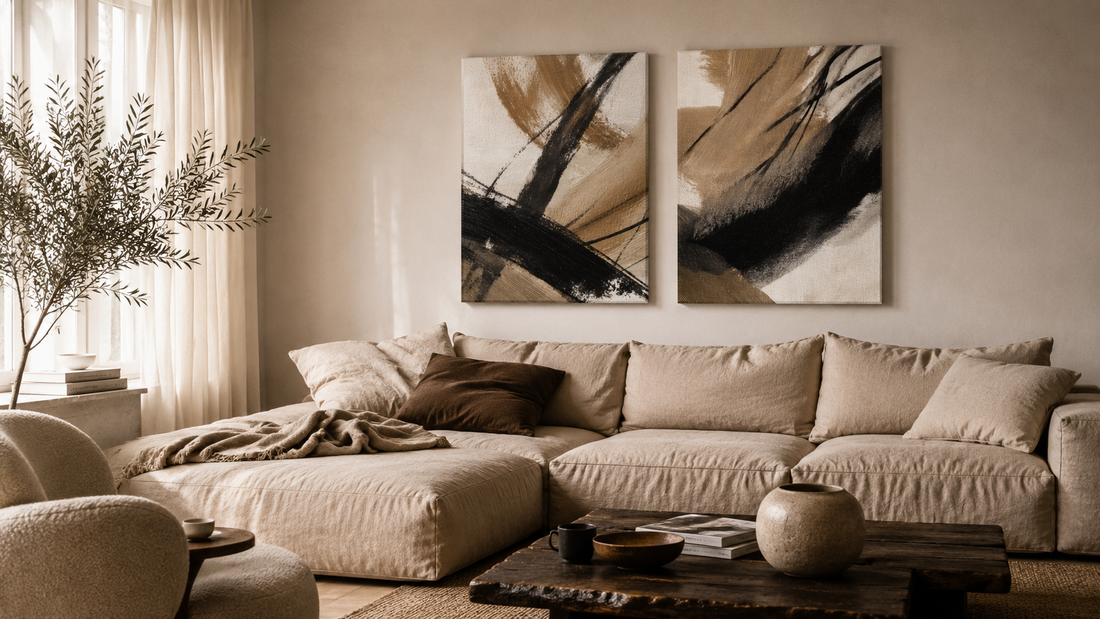 Pair of textured abstract canvas prints with visible brushwork above a linen sofa in a warm neutral living room
