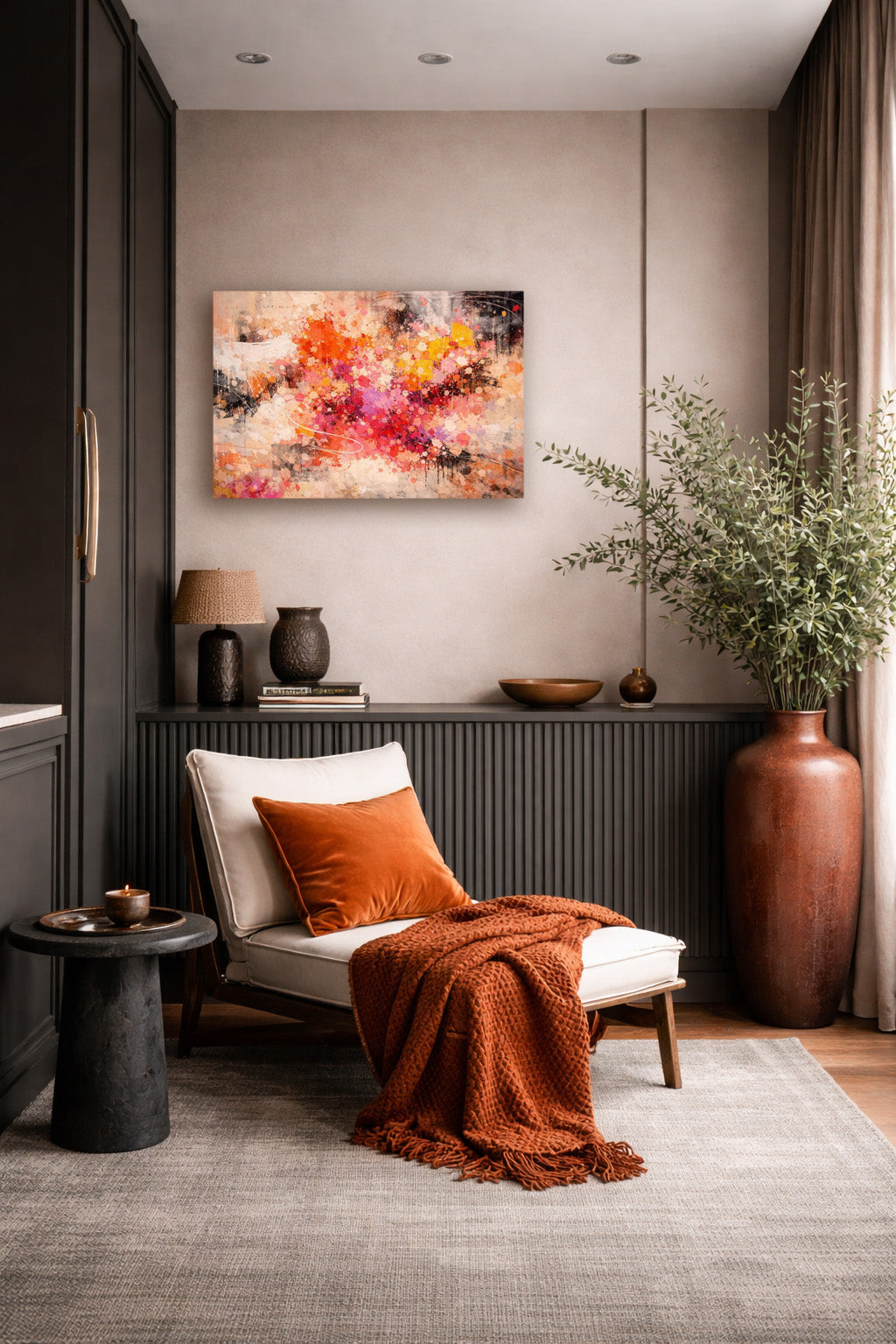 Abstract poster with pink, orange, and beige tones hanging above a cozy seating area with a rust-colored throw blanket, decorative pottery, and indoor plants.