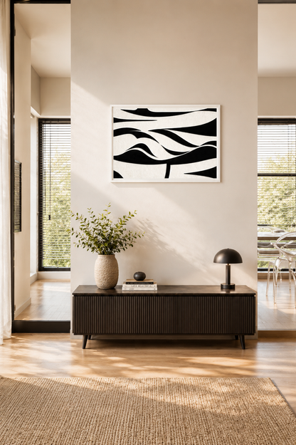 Black and white textured abstract wall art with a white wooden frame hanging above a dark wood console table in a bright Scandinavian-inspired interior.
