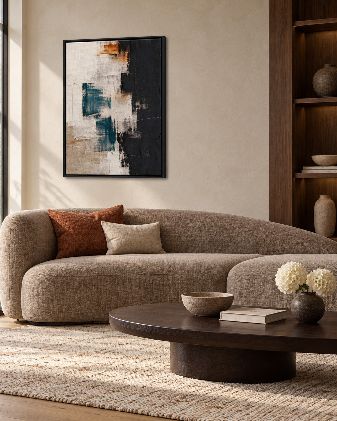 Framed teal, black and cream abstract canvas above a curved beige sofa with a rust-colored cushion.