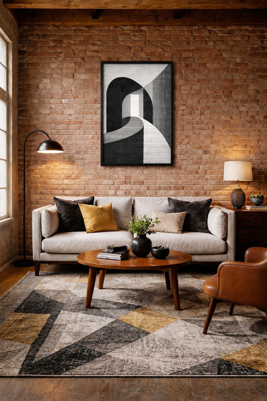 Black and white abstract wall art poster in a realistic black wooden frame displayed above a beige sofa in a cozy industrial living room with exposed brick walls and warm lighting.