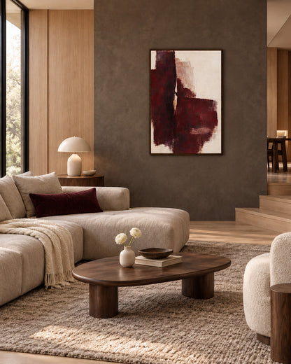 Oxblood Poise framed burgundy abstract poster on a taupe wall in a living room with cream seating and a wooden coffee table