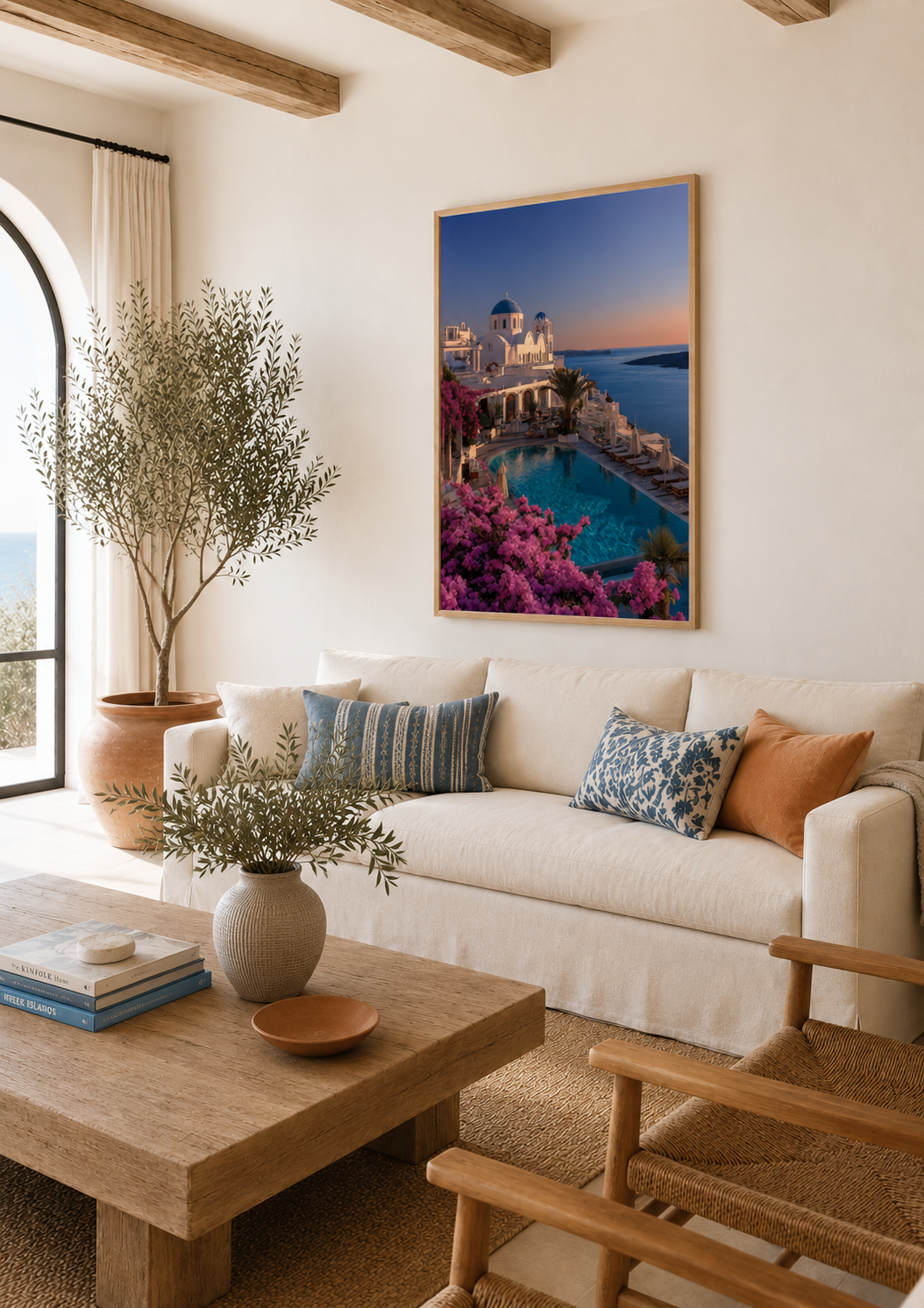 Framed Santorini sunset print above a linen sofa in a living room with wooden beams and an arched doorway