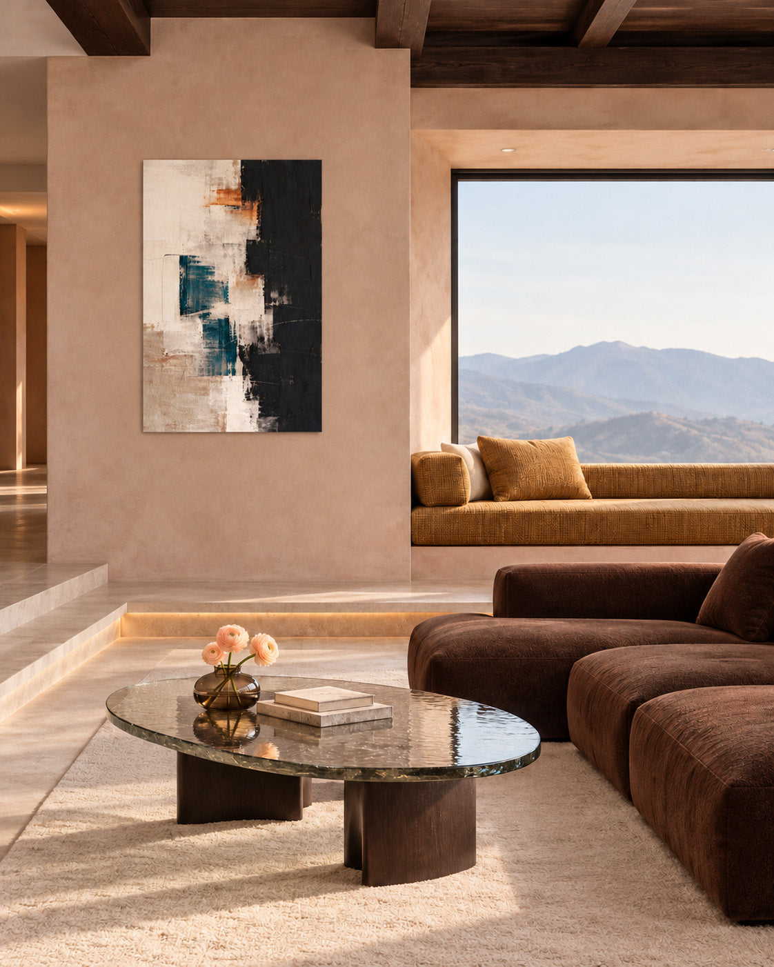 Teal, black and cream abstract poster on a beige living room wall beside brown seating and a large window with a mountain view.